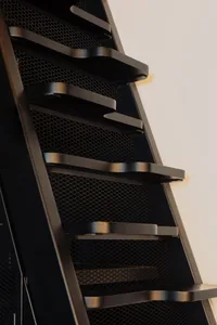 Modern, industrial-style metal staircase with black steps and railings.