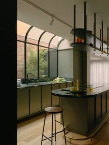 A modern kitchen featuring a marble countertop with greenery and a bar stool.