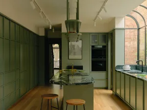 A well-lit residential kitchen featuring a green marble countertop and cabinets.