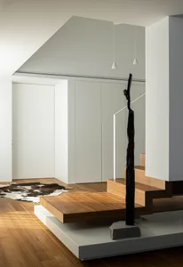 Modern interior design featuring a wooden staircase with minimalist design elements and white walls.
