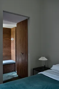 Minimalist bedroom featuring a dark wood cabinet and a bed with white linens.