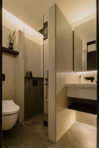 Modern bathroom interior with tiled walls, glass shower enclosure, and floating vanity with underlit storage.