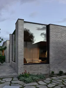 Modern building with glass and brick exterior, reflecting a cloudy sky.