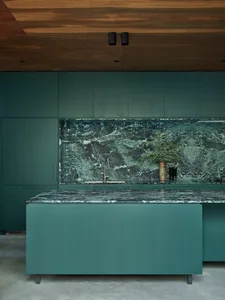 Contemporary kitchen with green marble countertops and backsplash, dark green cabinetry.
