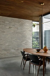 A modern industrial dining room featuring exposed brick walls, a wooden dining table, and black chairs.