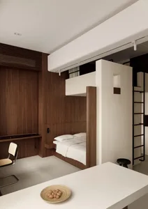 A modern minimalist bedroom featuring a built-in bed, wood-paneled walls, and concrete flooring.