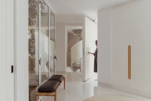 A minimalist interior space with white walls, wooden furniture, and a spiral staircase.