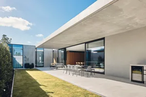 Modern residential building with concrete exterior, large windows, and outdoor dining area.