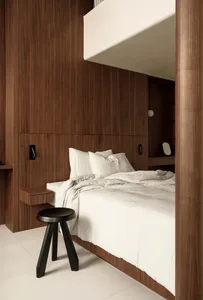 A minimalist bedroom with white bedding and wooden walls and floor.