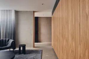 Minimalist residential interior with wood and concrete finishes, featuring a comfortable seating area and a modern aesthetic.