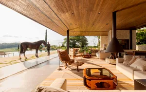 A modern living room featuring wooden furniture and large windows overlooking a serene outdoor landscape.