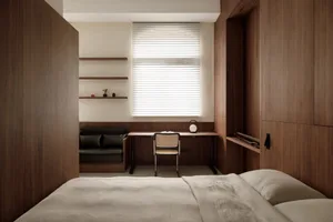 A minimalist bedroom with wooden walls and a white bed.