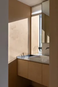 A minimalist bathroom with light-colored wooden cabinets and a sink.