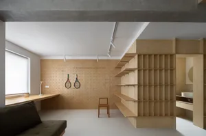 A minimalist residential space featuring wooden shelving and concrete walls.