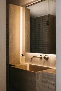 Modern bathroom with marble sink and faucet, illuminated by ambient lighting.