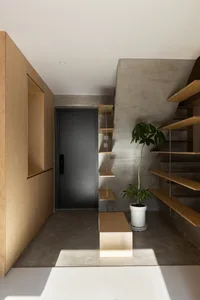 A modern entryway with concrete walls and wooden shelves and cabinets.
