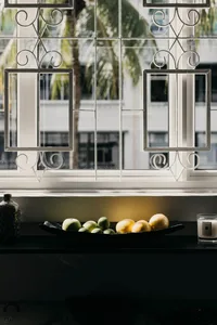 A modern kitchen counter with a white marble top, featuring a bowl of assorted green and yellow fruits.