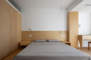 A minimalist bedroom with wood furniture and white walls.