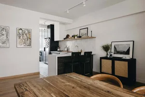 A modern open-plan kitchen dining room featuring black accents, white tile backsplash, and wooden countertops.