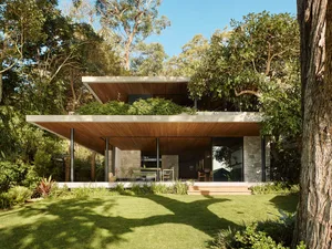 Modern residential exterior featuring wood, concrete, and stone materials.
