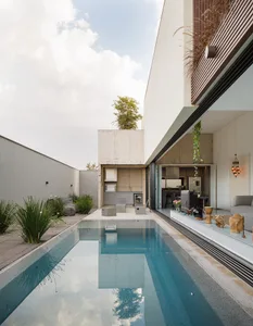 A modern residential backyard featuring a concrete swimming pool and surrounding greenery and landscaping.