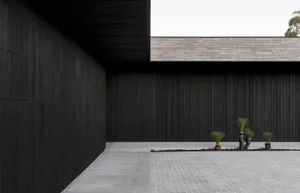 Modern building exterior with black concrete walls and a gray tiled floor.