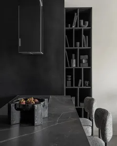 Modern kitchen featuring a black marble countertop and black shelves with various decor.