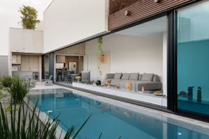 A modern minimalist living room with concrete, glass, and wooden elements.