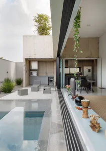 A modern residential swimming pool with concrete walls and a glass area.