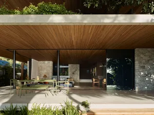 Modern, minimalist residential patio featuring wood elements, stone walls, and concrete flooring.