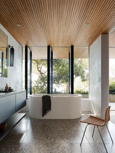 Modern minimalist bathroom featuring concrete walls, a freestanding bathtub, and wooden ceiling.