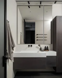 A modern minimalist bathroom featuring a floating vanity with a concrete countertop and dark wood base, complemented by a lar