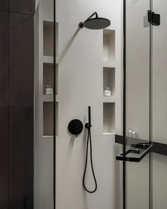 A modern minimalist bathroom featuring a textured white tiled wall and a glass partition. The bathroom includes a shower area