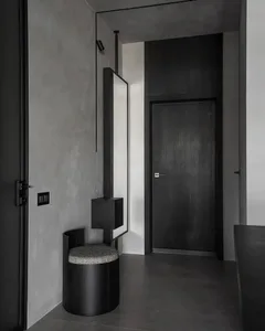 A modern minimalist entrance hall with concrete walls and black furniture.