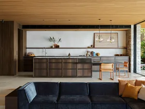 A modern minimalist kitchen with wooden cabinets, concrete countertops, and glass pendant lights.