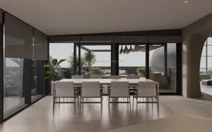Modern minimalist living room featuring metal and glass furniture on a concrete floor.