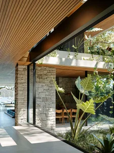 A modern residential interior featuring stone, wood, and glass materials.