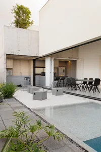 Modern outdoor residential area with concrete flooring, swimming pool, and kitchen area