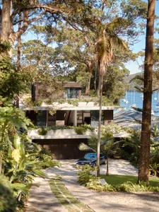 Modern waterfront home with stone, concrete, and glass exterior materials.