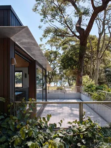 Modern building exterior made of concrete, surrounded by lush greenery and trees.
