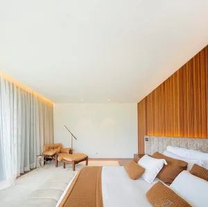 A modern bedroom featuring a large bed with white linens and brown accent pillows, a wooden headboard, and a floor lamp next 
