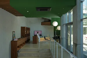 Modern lobby interior with concrete walls, large windows, and minimalist furniture.