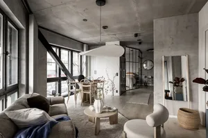A modern minimalist living room with concrete walls, natural light, and contemporary furniture.