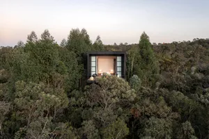 A minimalist treehouse with wood, glass, and steel materials.