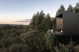 A modern, metal-clad building nestled in a forest.