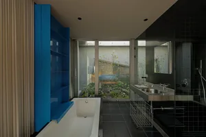 A modern bathroom with glass walls and a white bathtub.