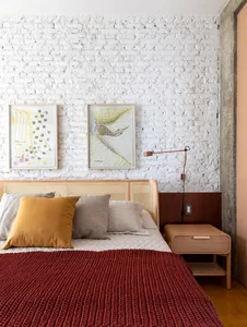 Modern bedroom with a white brick wall, textured concrete headboard, and a red blanket on the bed.