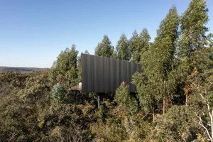 A modern metallic building exterior surrounded by trees