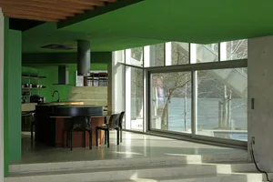 A modern interior design with concrete walls and floor, large glass windows, and a kitchen island.