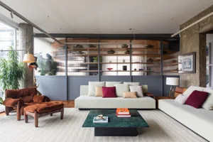 A modern living room featuring a concrete wall, white sofas, and a green marble coffee table.